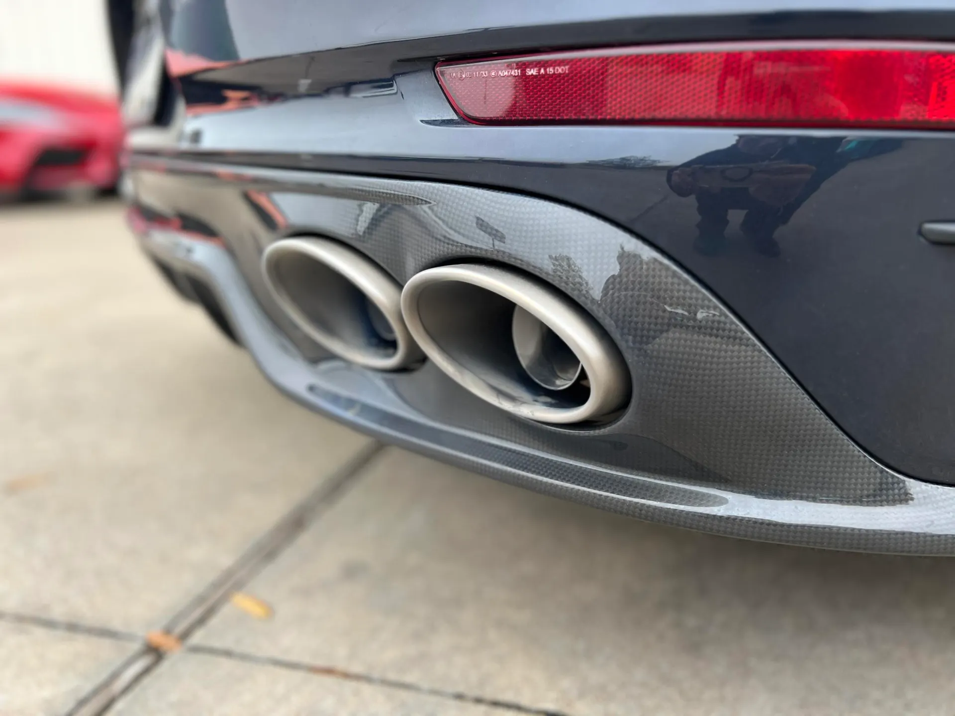 Close-up of a grey Porsche's rear bumper featuring dual exhaust tips and a carbon fiber diffuser.