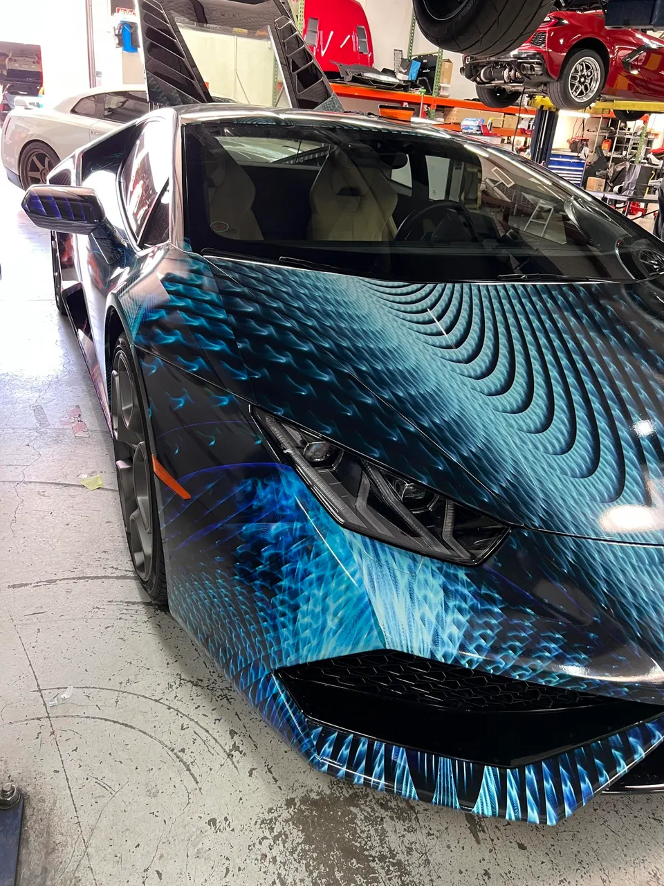 Lamborghini Huracan with a custom blue and black wrap parked in a performance tuning shop.