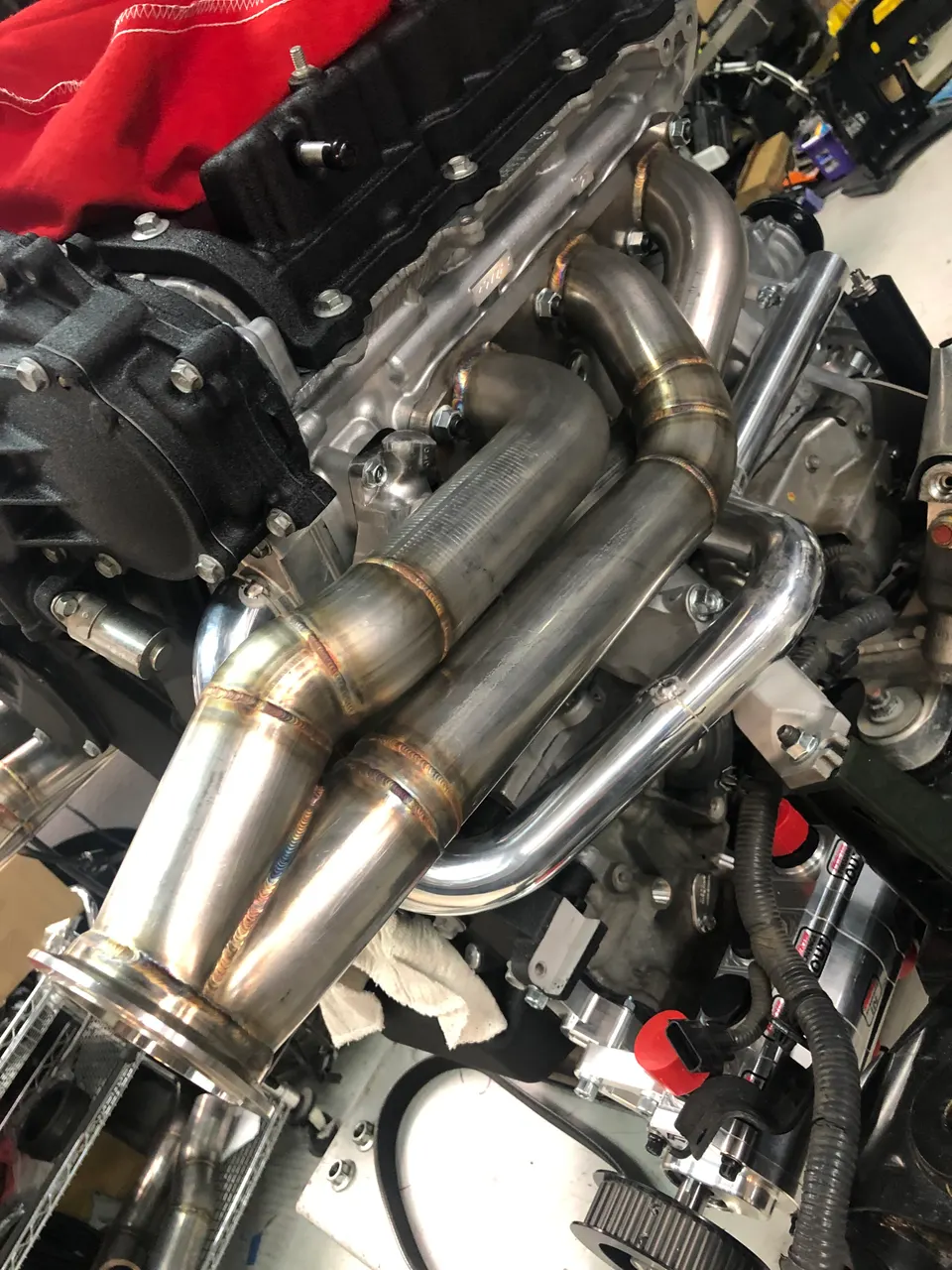 Close-up of a custom fabricated exhaust manifold installed on a performance engine during a build in a shop.