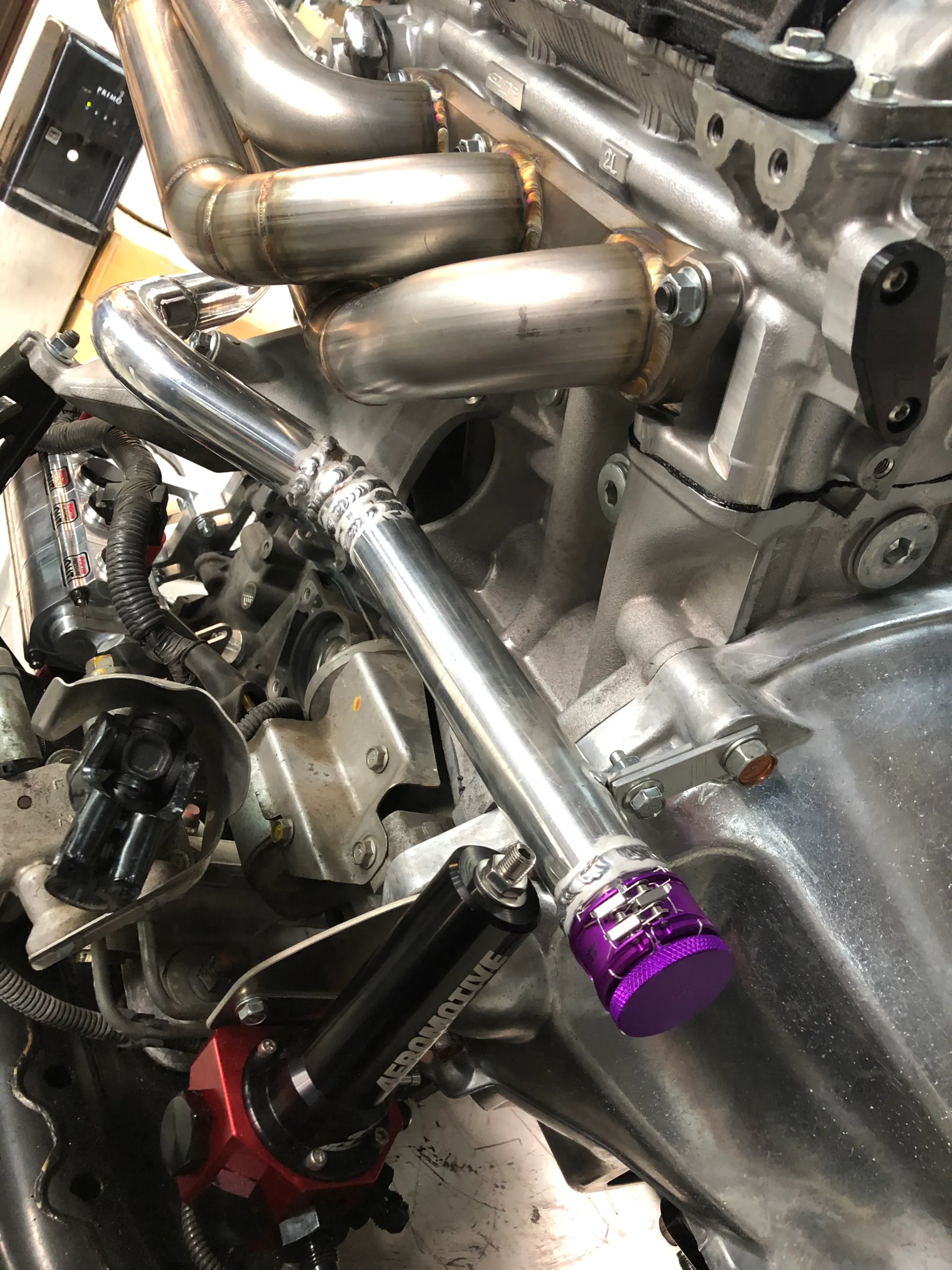 Close-up of custom fabricated exhaust headers and Aeromotive fuel system components on a performance engine.