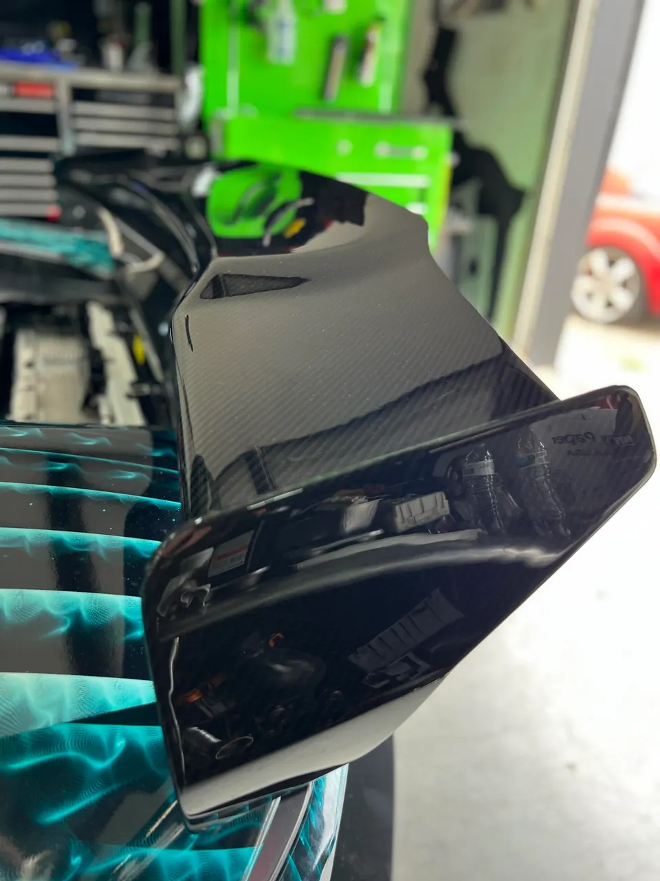 Close-up of a carbon fiber spoiler on a performance car in a shop setting