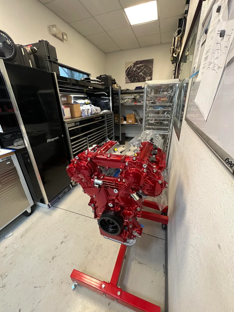 Red built engine on an engine stand in a performance tuning shop, ready for installation.