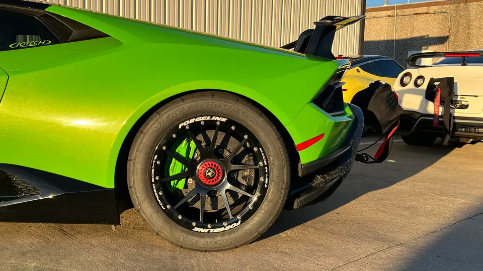 Green Lamborghini Huracan with Forgeline wheels, Mickey Thompson drag tires, and a large rear wing, parked outdoors.