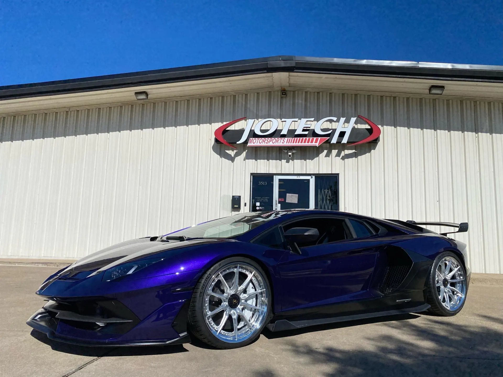 Purple Lamborghini Aventador with aftermarket wheels and aero kit parked in front of Jotech Motorsports.