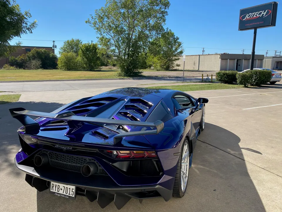 Rear view of a purple Lamborghini Aventador with a large rear wing and aggressive diffuser parked at Jotech Motorsports.