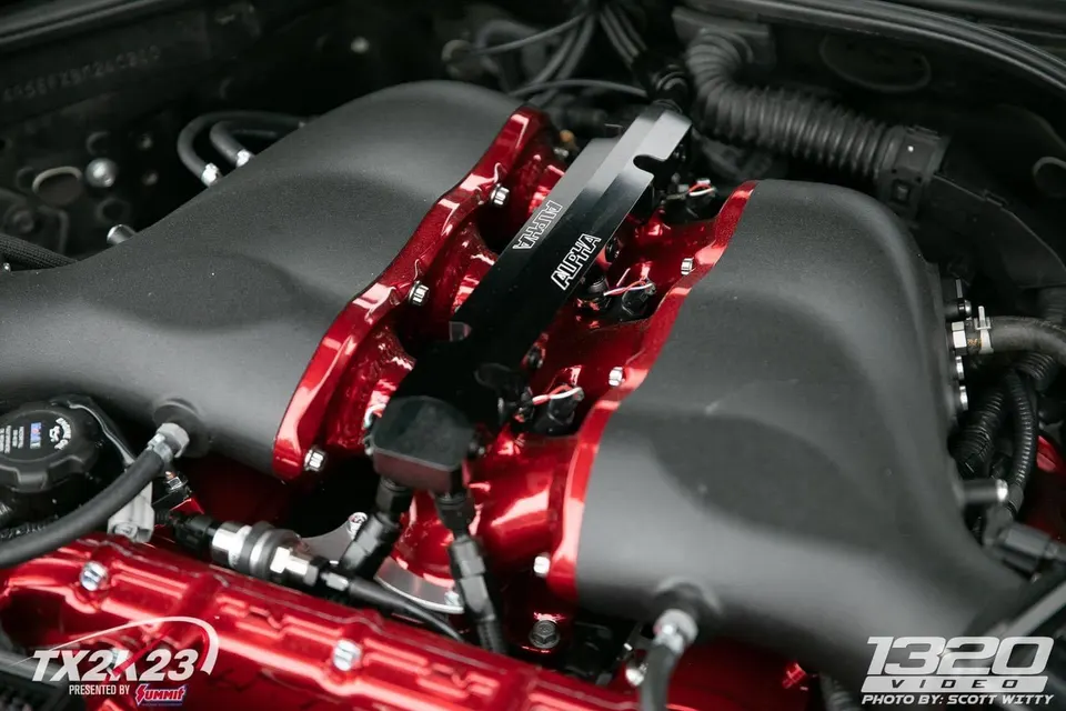 Close-up of a high-performance engine bay featuring a red Alpha Performance intake manifold and custom fuel lines.