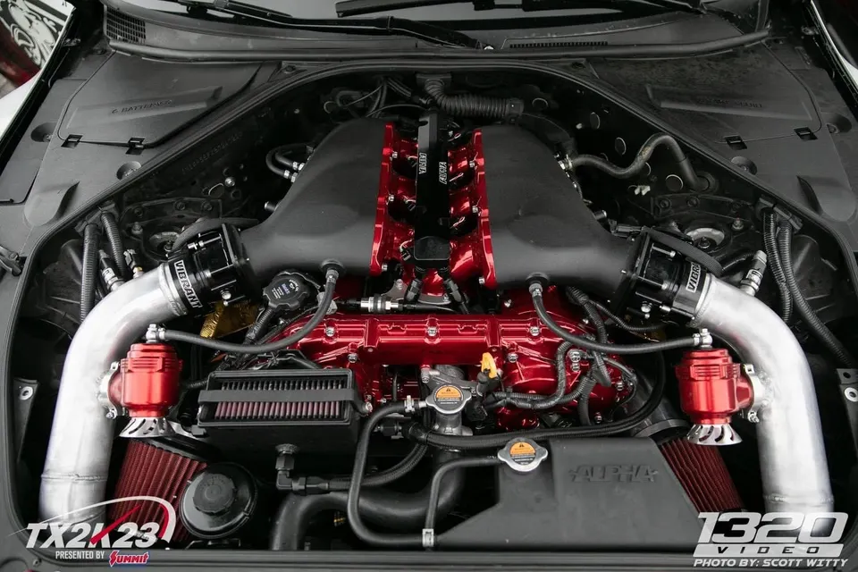 A highly modified Nissan GT-R engine bay featuring custom red intake manifold, Vibrant blow-off valves, and Alpha Performance components.
