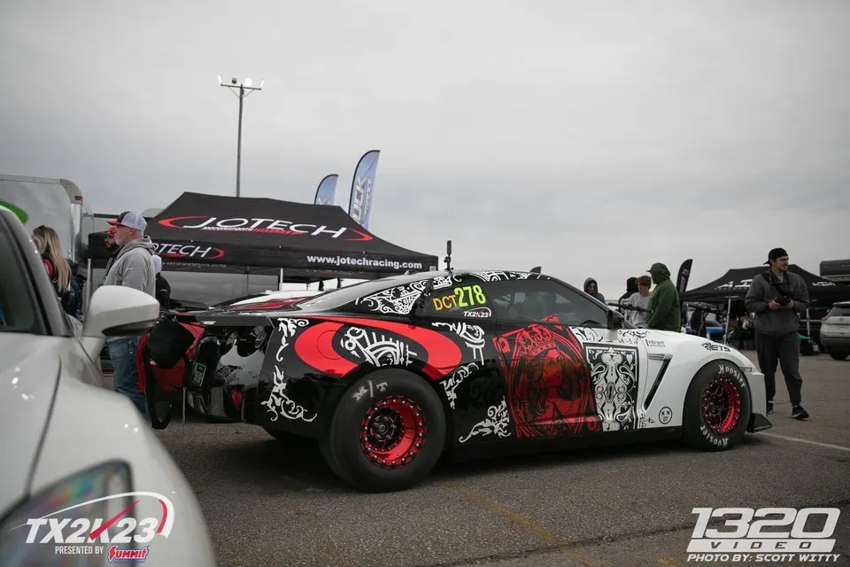 Highly modified Jotech Nissan GT-R drag car with custom black, red, and white wrap and drag slicks at TX2K23 event.