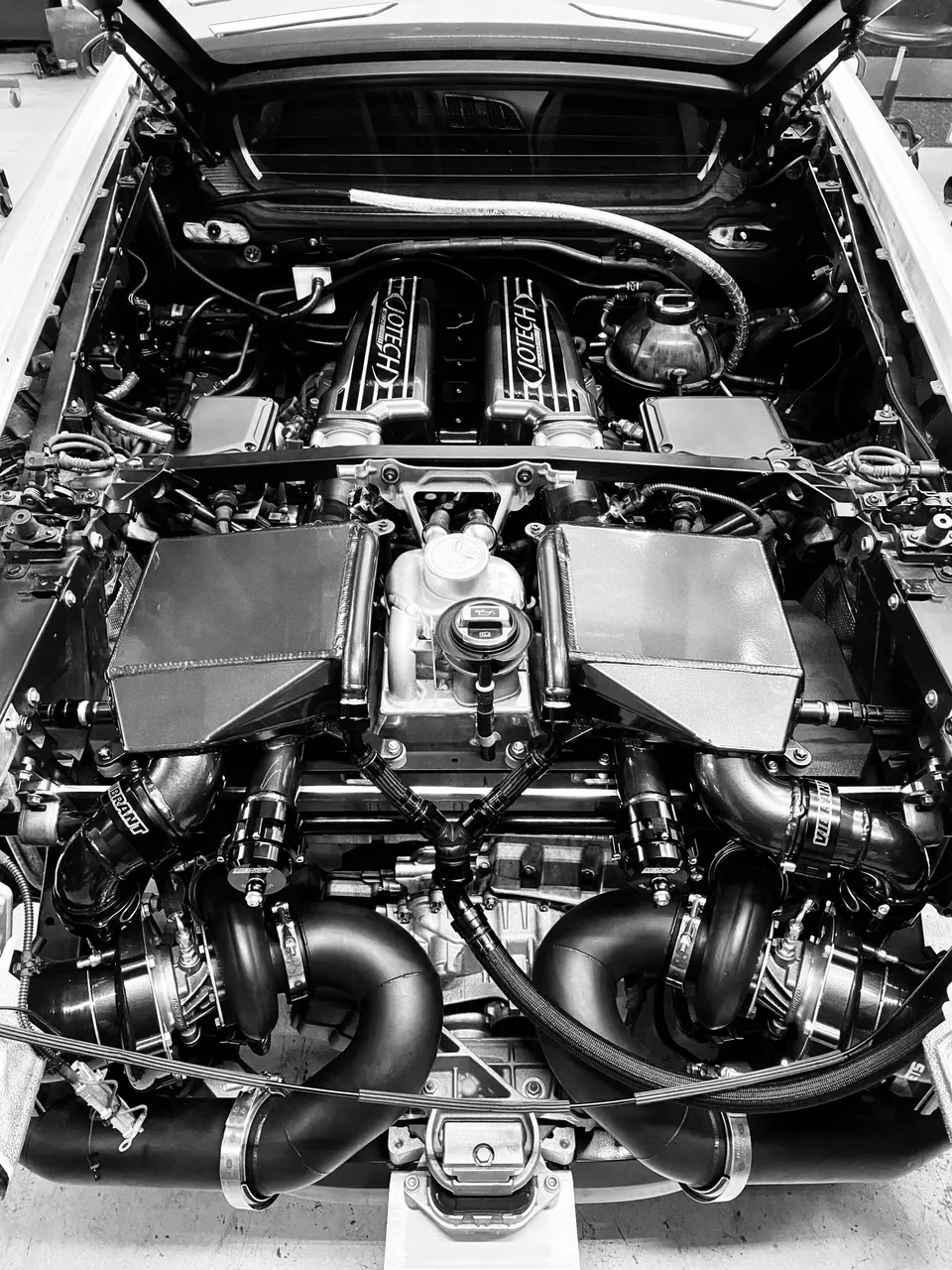Overhead view of a Jotech twin-turbo performance engine bay with custom piping and components.