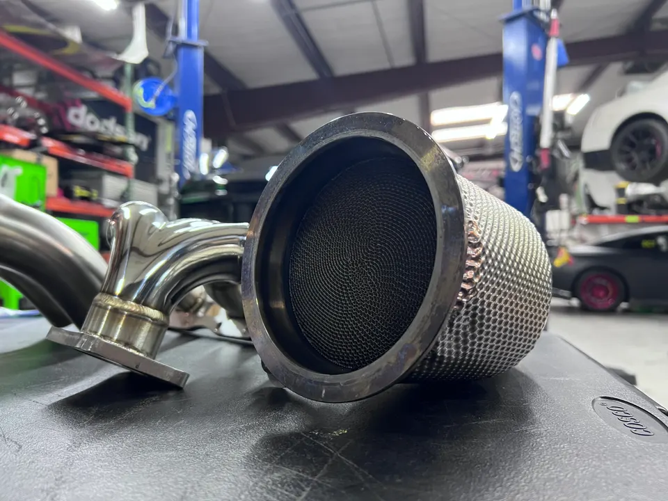 Close-up of a performance catalytic converter or exhaust component on a table in a tuning shop.