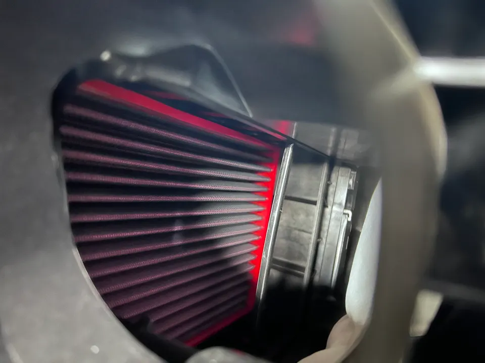 Close-up view of a performance air filter inside an induction system, showcasing the red filter element.