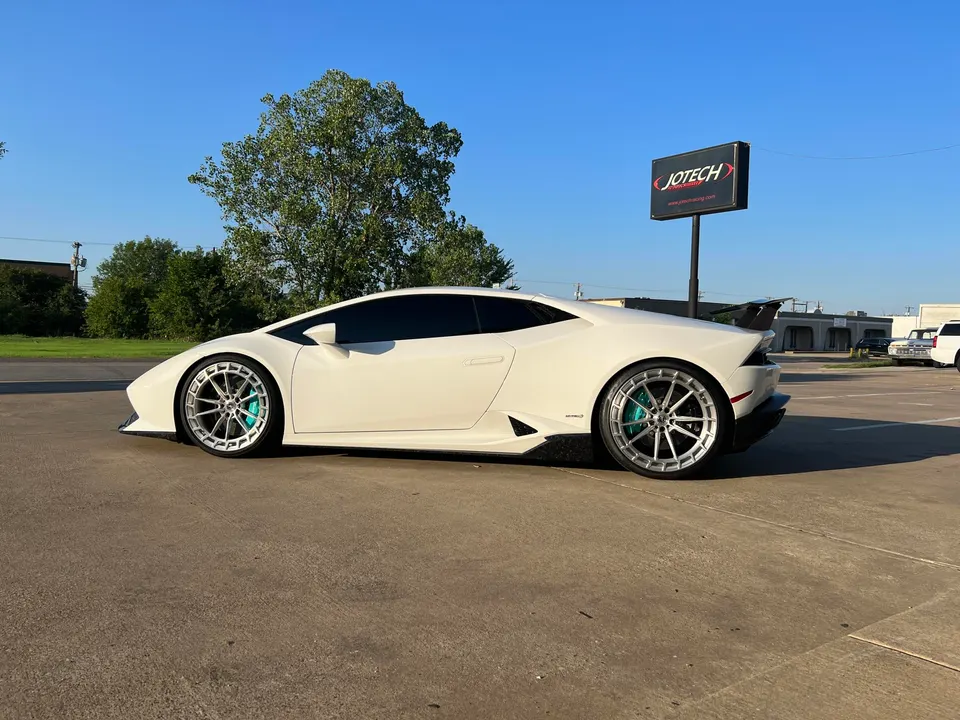White Lamborghini Huracan with aftermarket wheels and a rear wing parked outside Jotech Motorsports.