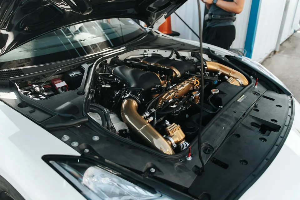 Close-up of a Nissan GT-R engine bay featuring custom gold intake and boost piping with a black intake manifold.