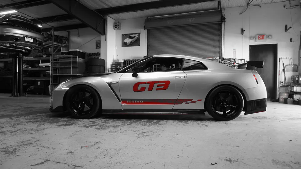 Silver Nissan GT-R R35 with GT3 Nismo livery and black wheels parked in a performance tuning shop.