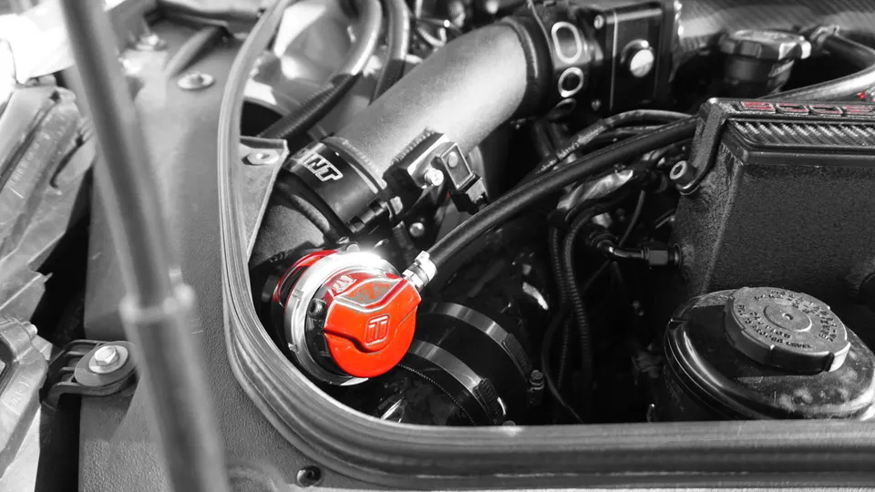 A close-up view of a red blow-off valve installed in a high-performance car's engine bay, showcasing aftermarket turbo components.