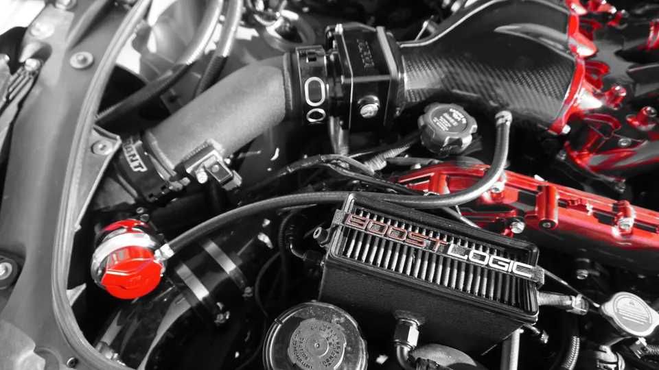 Close-up of a high-performance engine bay featuring a Boost Logic turbo system and carbon fiber intake components.