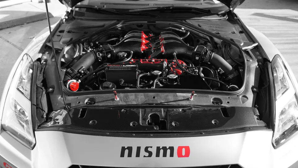 Close-up of a Nissan GT-R R35 engine bay featuring carbon fiber induction system and red accents.