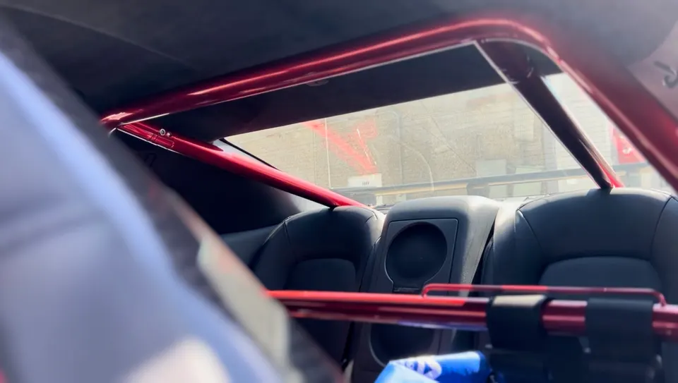 Close-up of a red roll bar installed in the rear interior of a performance car, visible over the rear seats.