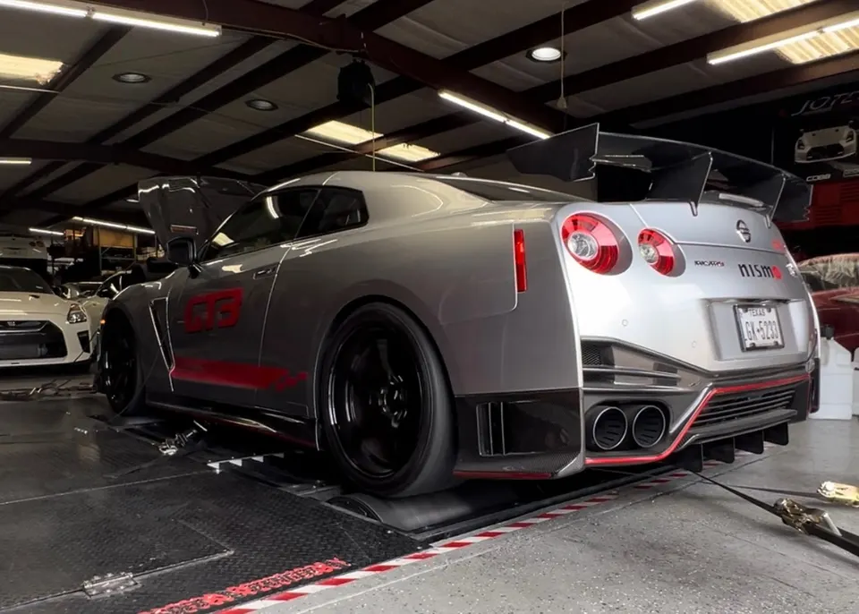 Silver Nissan GT-R Nismo on a dynamometer, showcasing its rear exhaust system and large carbon fiber wing.