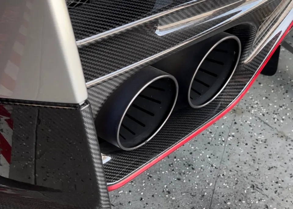 Close-up of a car's dual black exhaust tips integrated into a carbon fiber rear diffuser.