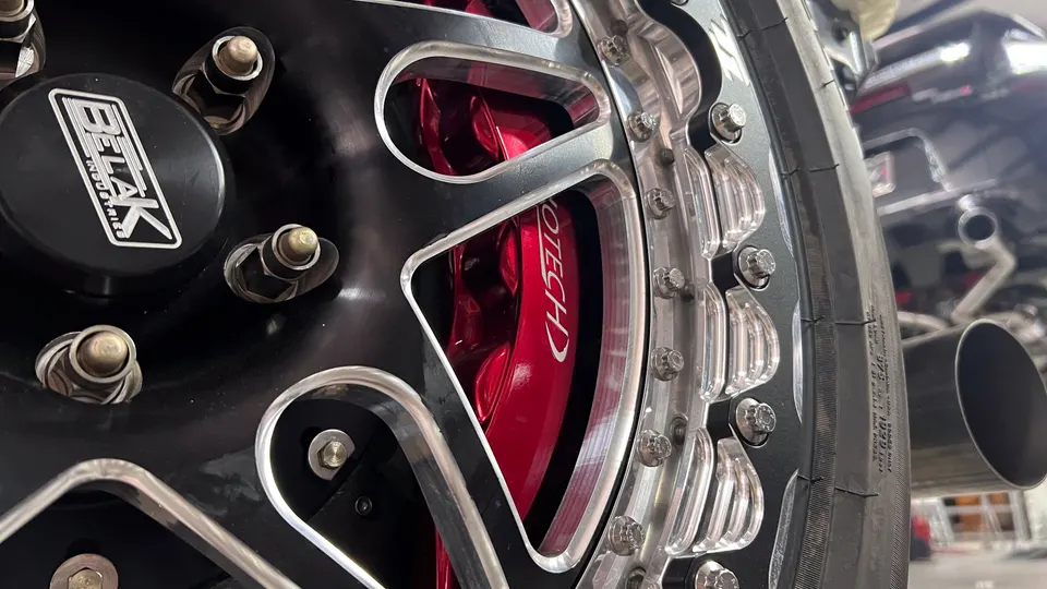 Close-up of a black Belak wheel with red Jotech Rototech brake calipers and a performance tire.