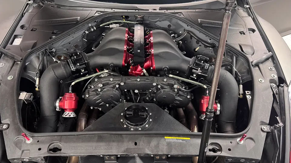 Close-up of a highly modified Nissan GT-R engine bay showcasing a custom intake manifold and performance induction system.