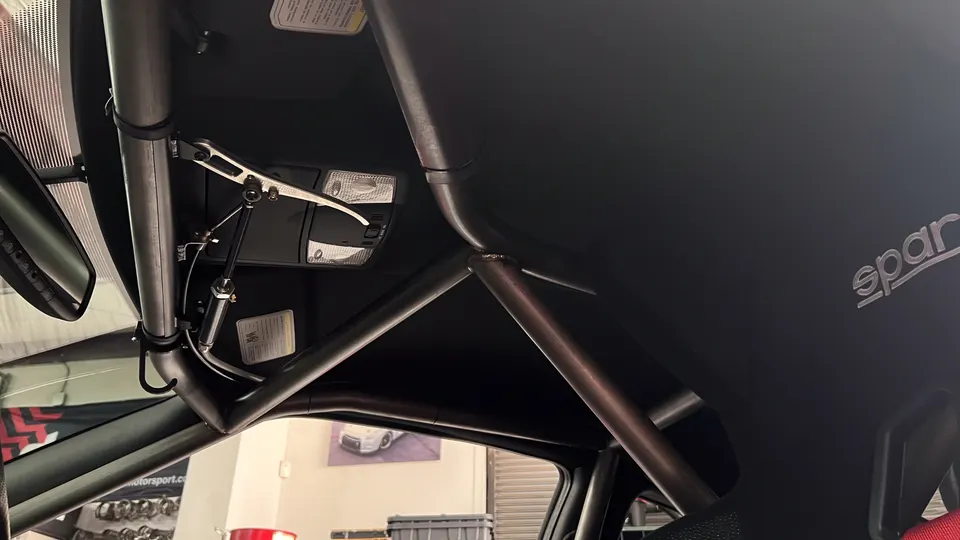 Interior view of a custom roll cage and Sparco racing seat in a performance car.