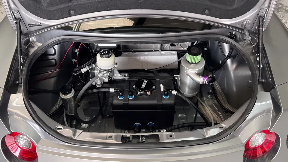 A custom fuel cell and upgraded fuel system components installed in the trunk of a performance car.