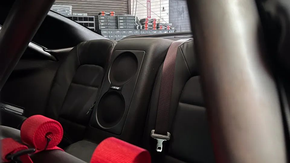 Interior view of a Nissan GT-R showing rear seats, Bose speakers, and a red roll bar.