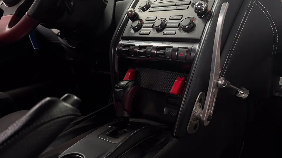 Close-up of a Nissan GT-R interior showing the center console, shifter, and custom hydraulic handbrake.