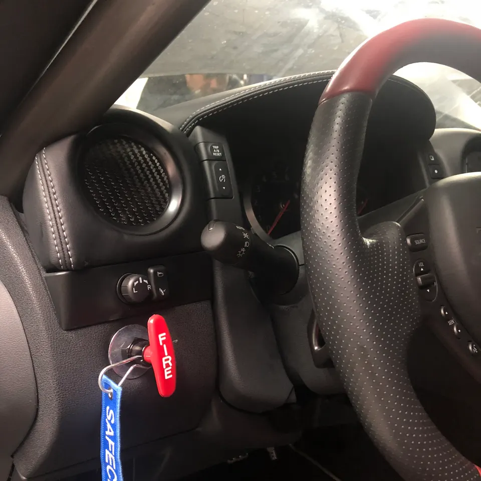 Close-up of a Nissan GT-R interior showing a red fire extinguisher pull, carbon fiber air vent, and steering wheel.