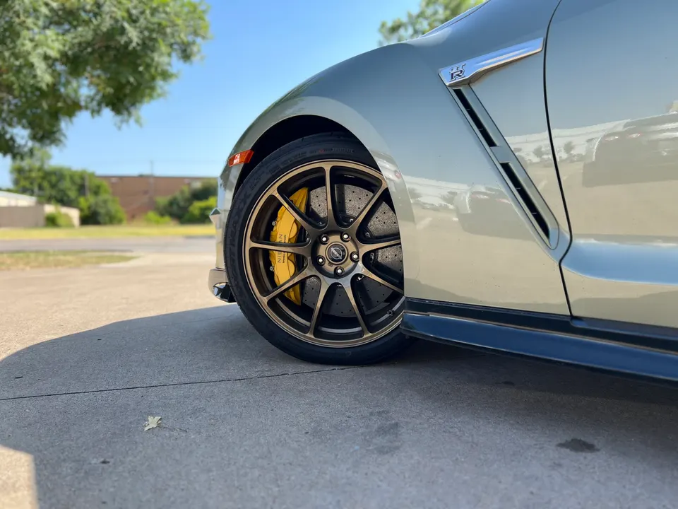 Close-up of a Nissan GT-R's bronze aftermarket wheel with yellow brake calipers and drilled rotors.