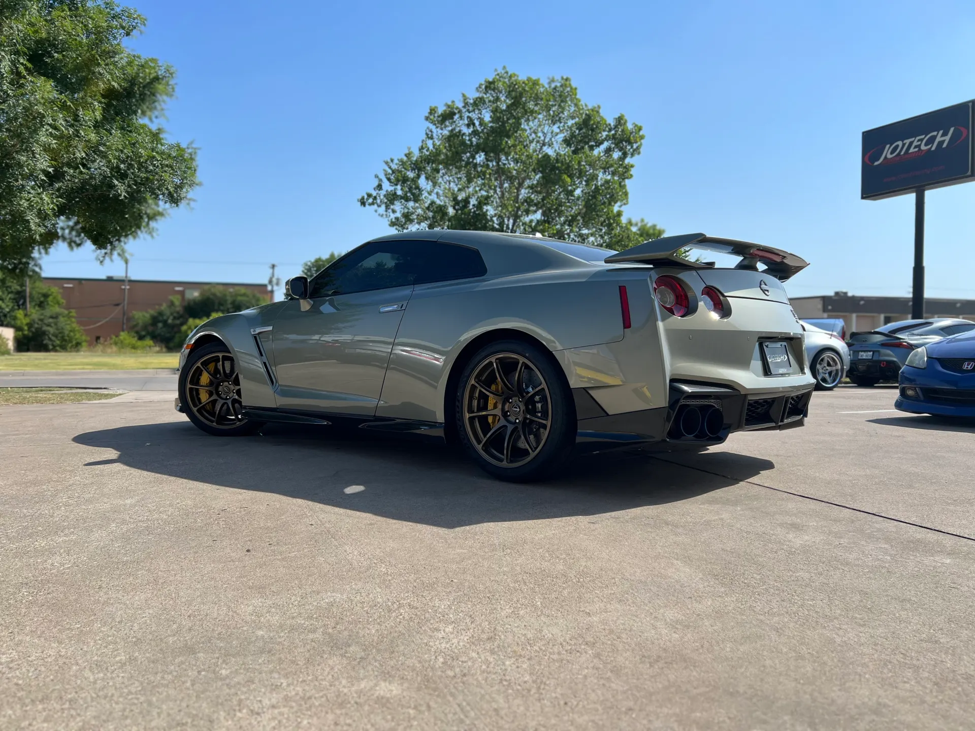 Light green Nissan GT-R R35 with aftermarket wing and bronze wheels parked outside Jotech Motorsports.