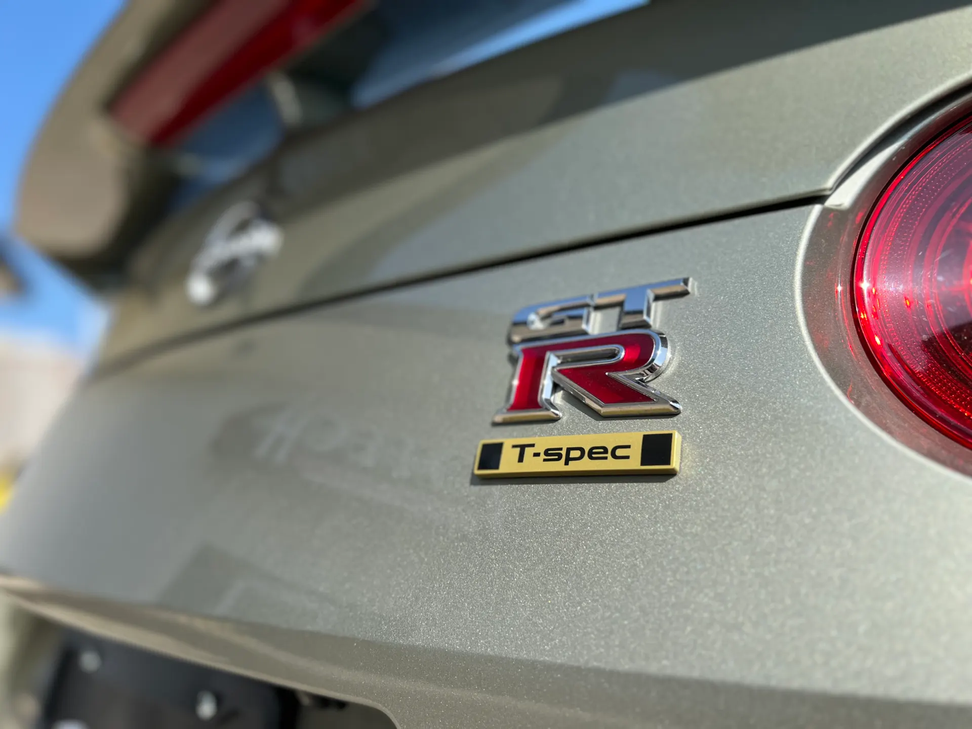 Close-up of a Nissan GT-R T-spec emblem and taillight on the rear of the car.