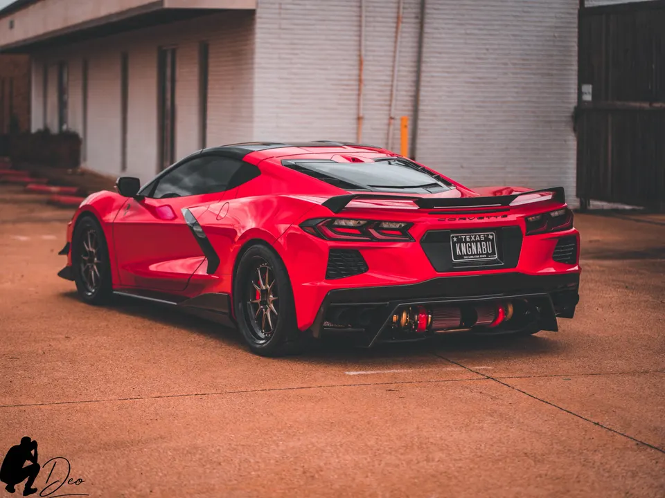 Red Chevrolet Corvette C8 with aftermarket wheels, carbon fiber rear wing, diffuser, and exposed induction filters.