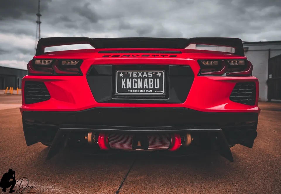 Red C8 Corvette rear view showcasing custom turbo setup and diffuser under a dramatic sky.