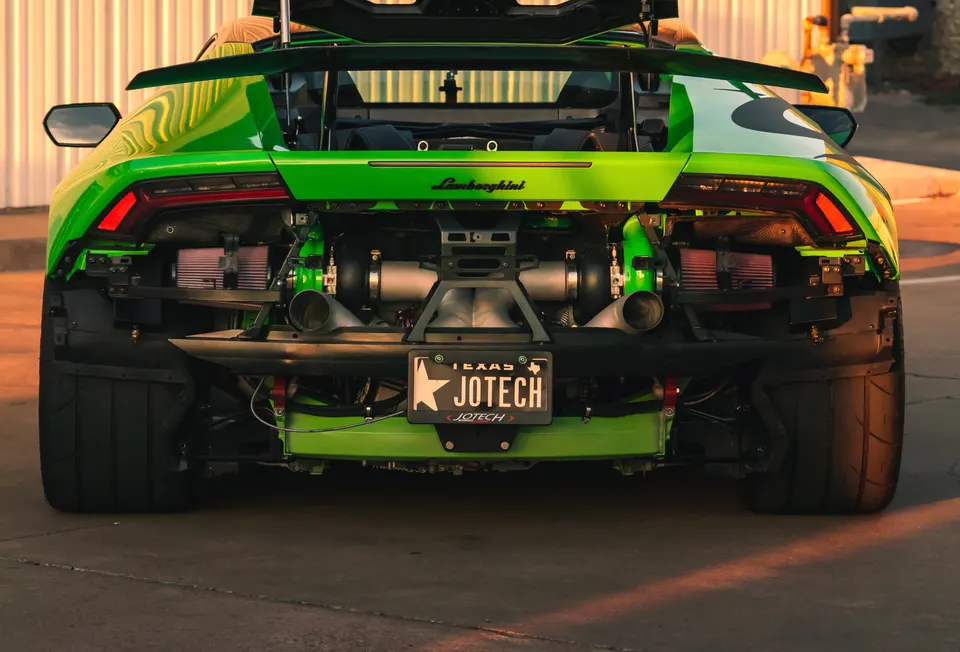Rear view of a green Lamborghini Huracan with exposed twin-turbo setup and Jotech license plate.