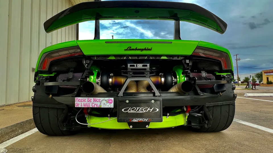 Rear view of a green Lamborghini Huracan with exposed twin turbochargers and custom exhaust system, featuring a Jotech license plate frame.