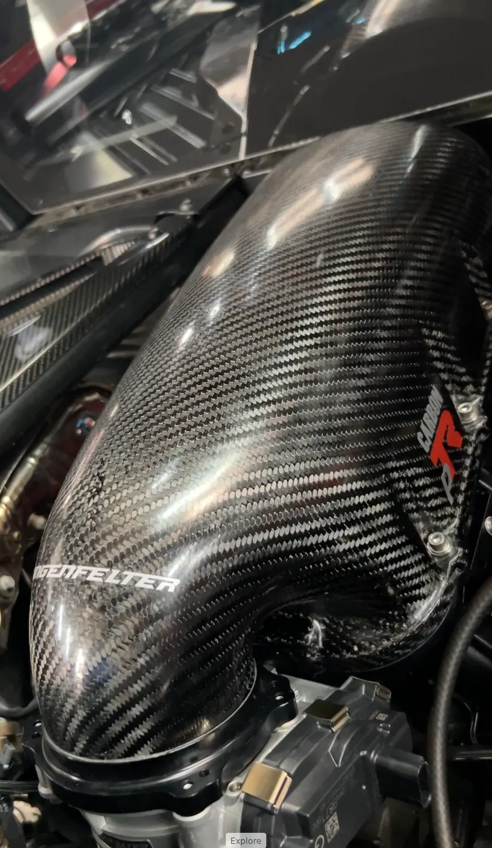 A close-up of a Lingenfelter carbon fiber intake system in an engine bay.
