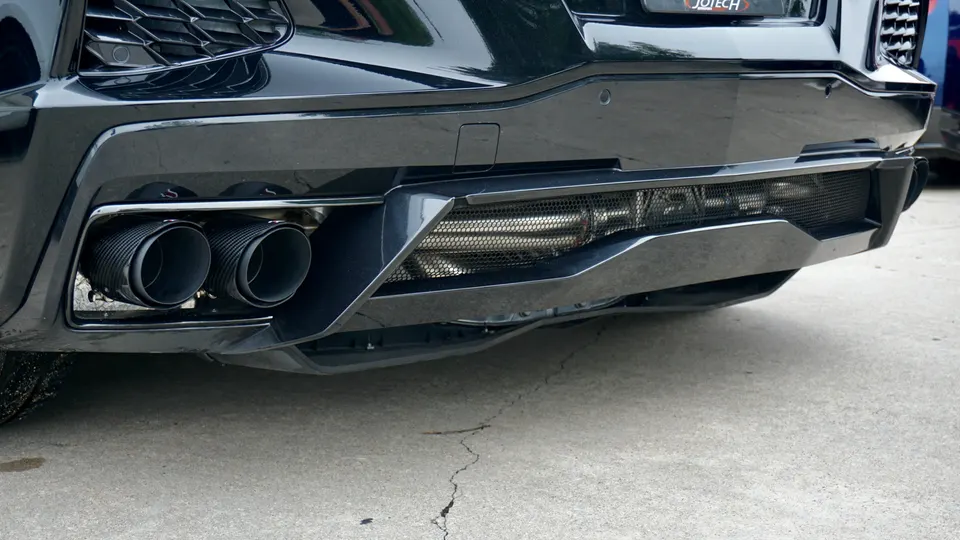 Close-up of the rear bumper and custom exhaust system of a black performance car, possibly a Jotech build.