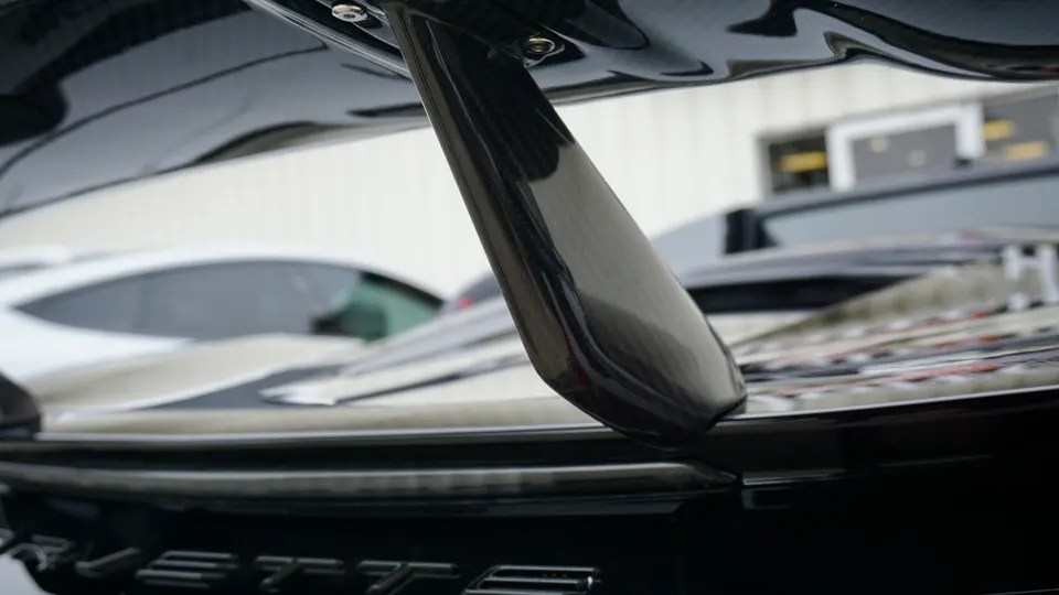 A close-up of a black carbon fiber rear wing on a Corvette.