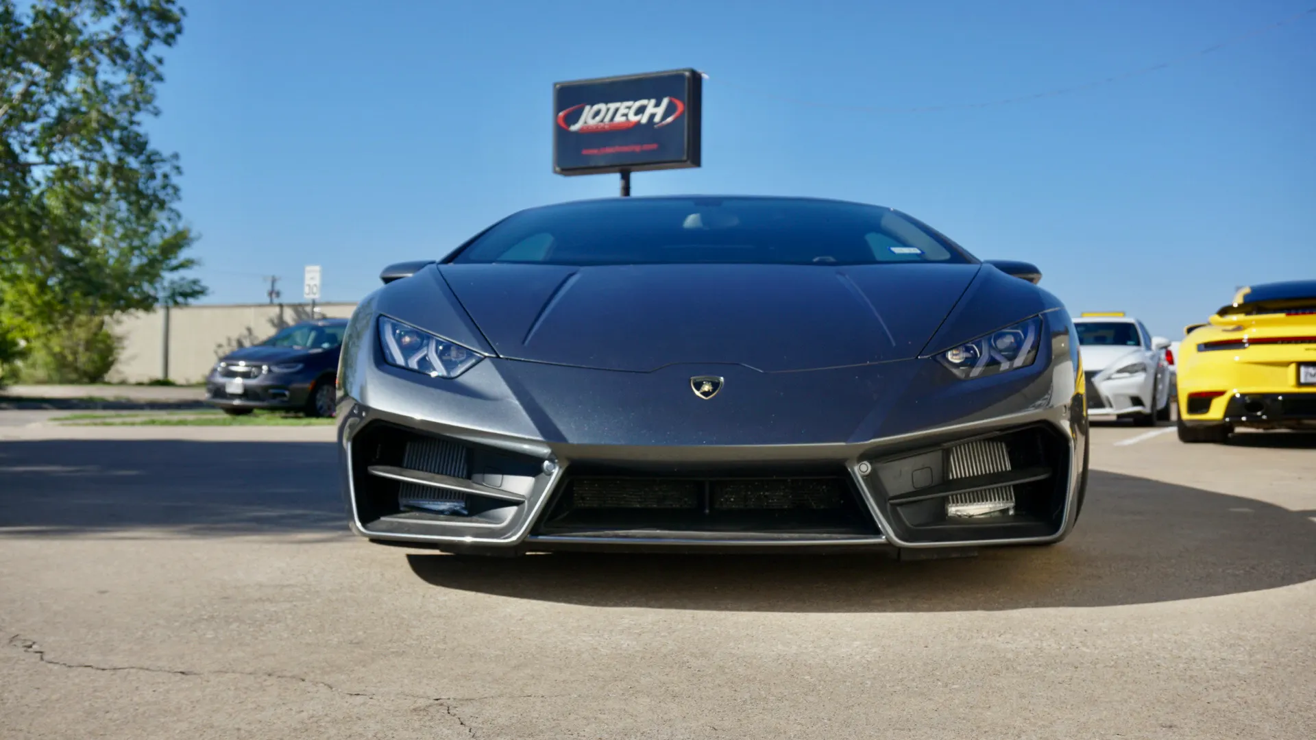 Front view of a grey Lamborghini Huracan supercar parked outside Jotech Motorsports shop.