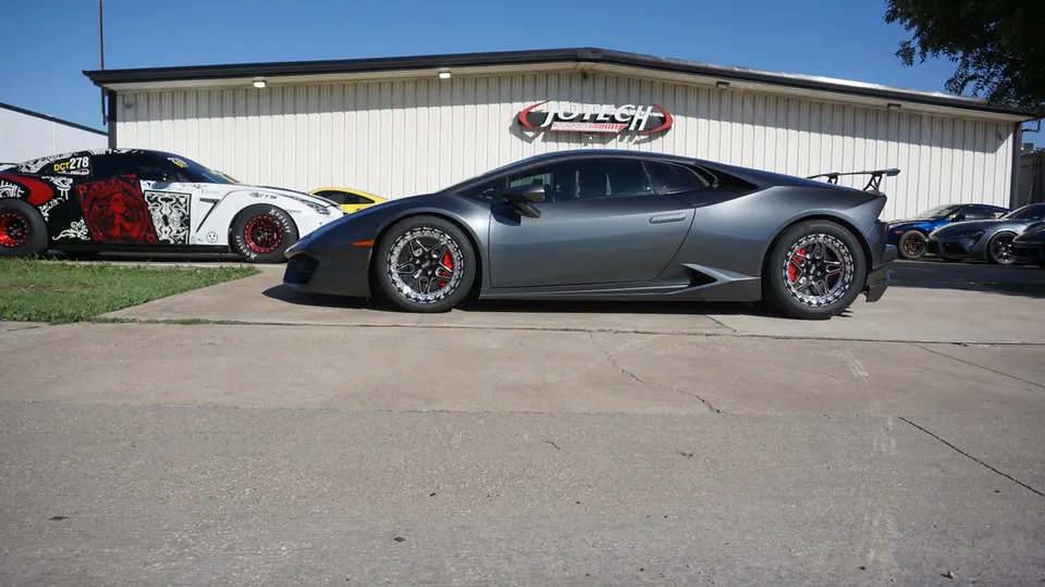 A grey Lamborghini Huracan and a custom-wrapped Nissan GT-R parked outside Jotech Motorsports performance shop.