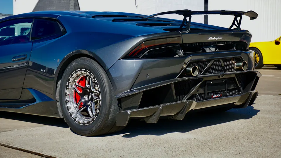 Dark grey Lamborghini Huracan with a large carbon fiber rear wing, aggressive diffuser, and drag racing wheels.