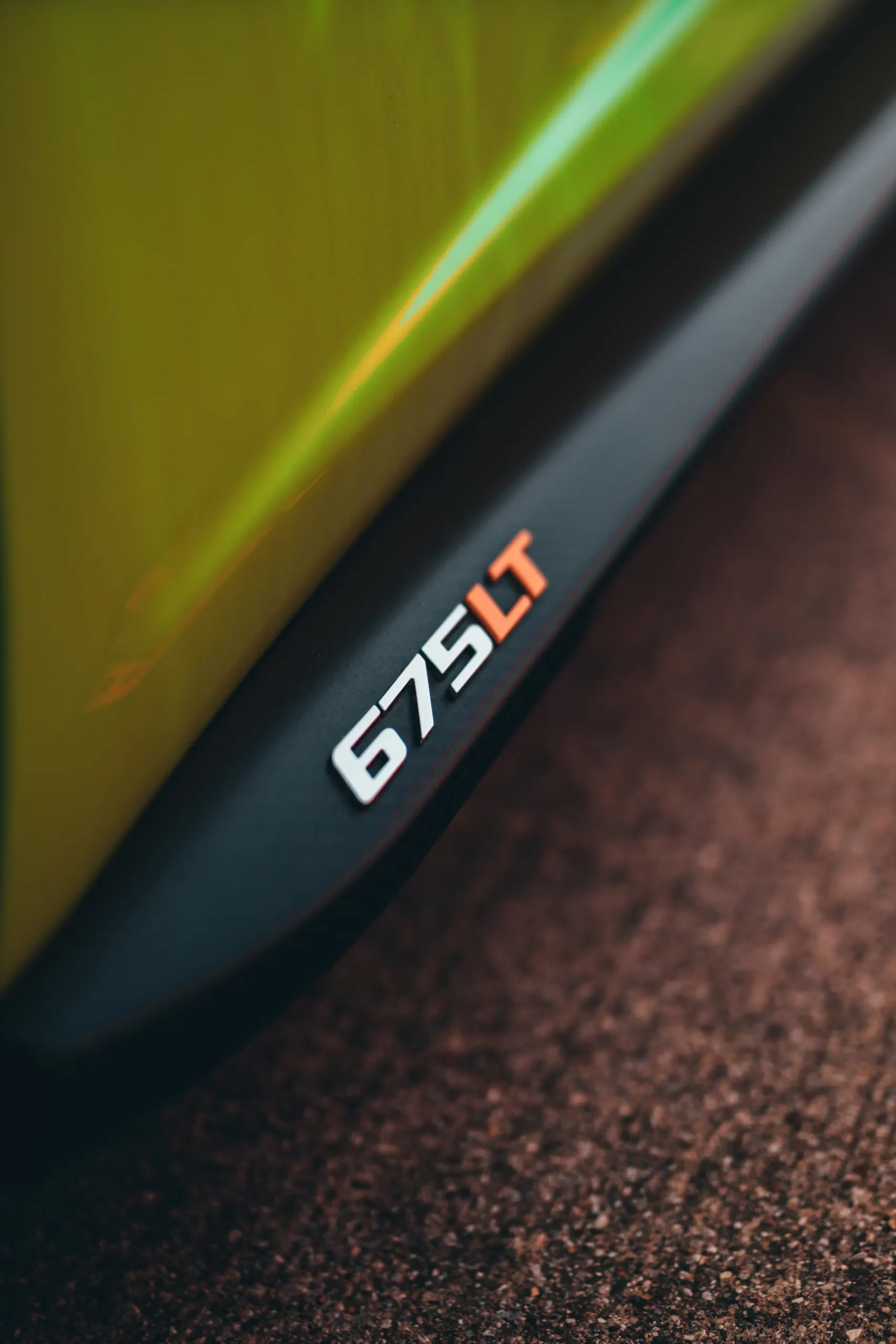 Close-up of the McLaren 675LT badge on the side of a yellow supercar.
