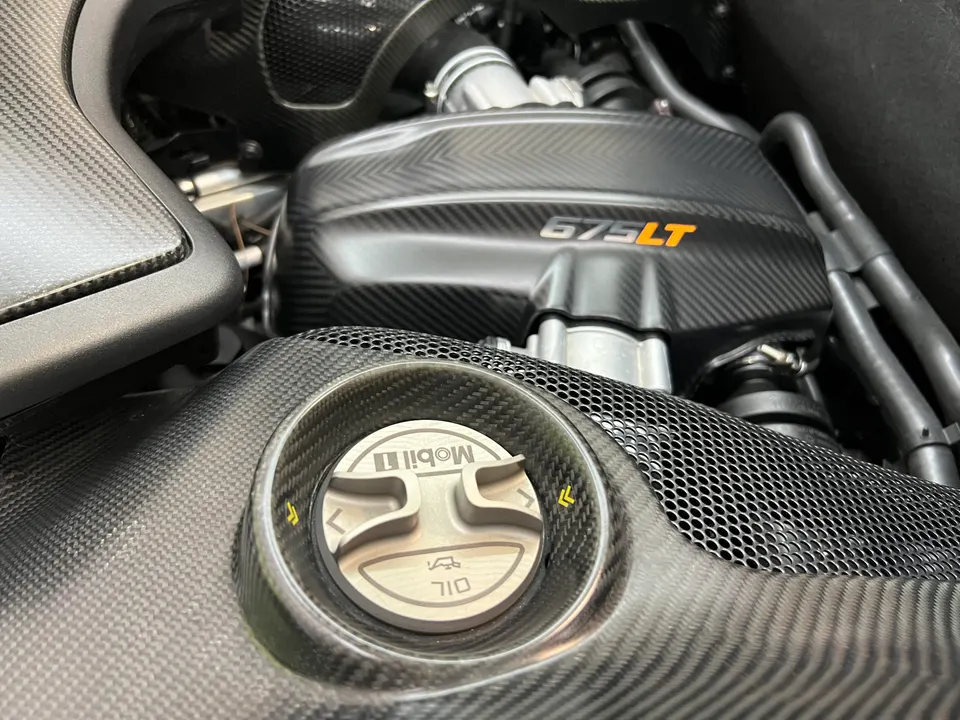 Close-up of a McLaren 675LT engine bay featuring carbon fiber components and a Mobil 1 oil cap.