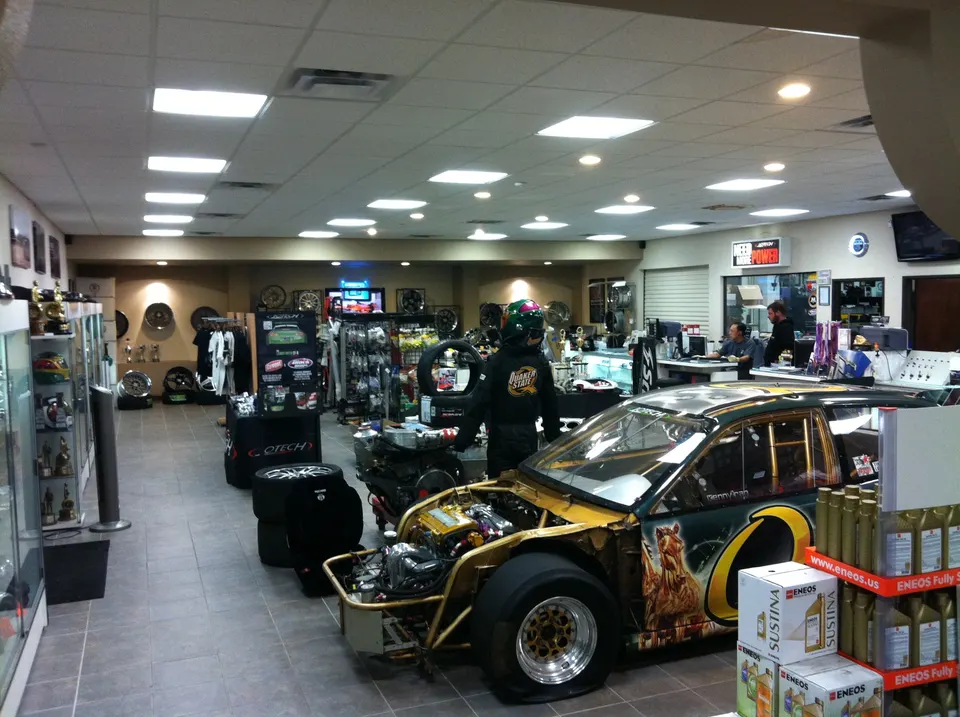 A highly modified drag race car with an exposed engine bay on display in a performance tuning shop.