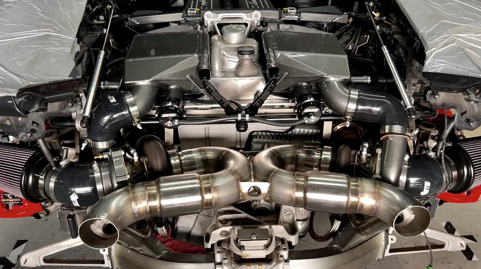 Close-up of a Lamborghini engine bay featuring a twin-turbo setup with custom exhaust and intake components.