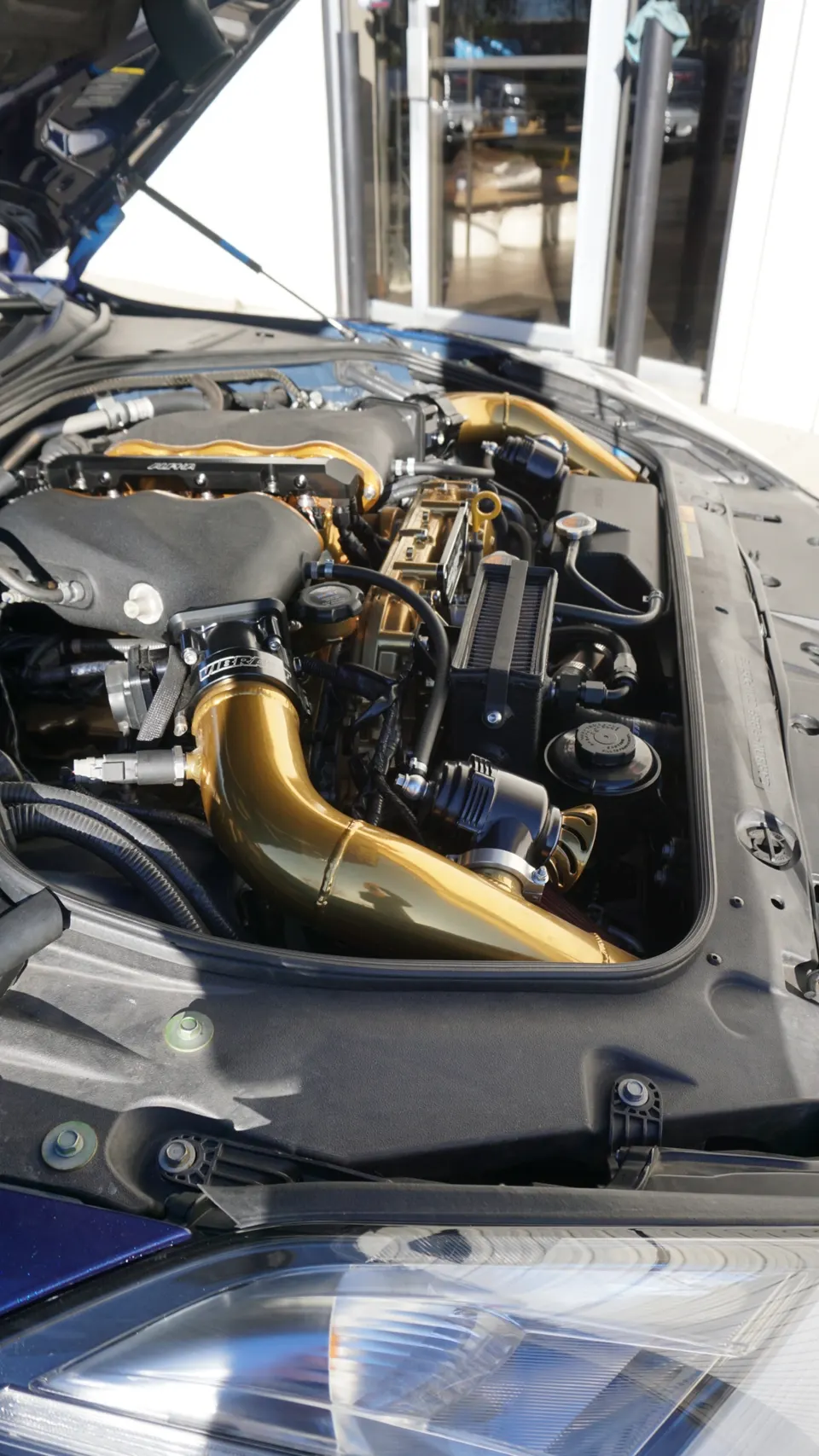 Detailed view of a Nissan GT-R engine bay featuring gold aftermarket turbo boost pipes and performance components.
