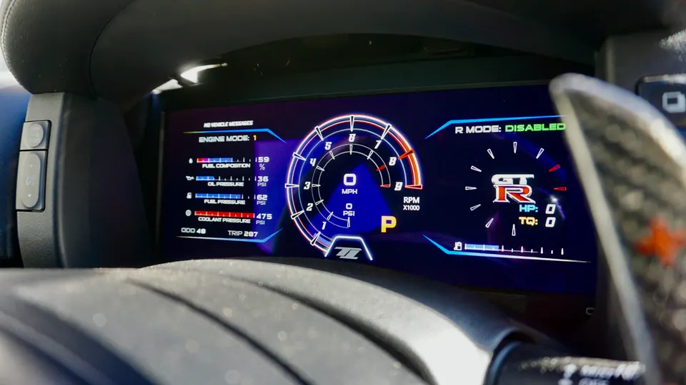 A close-up of a Nissan GT-R's digital dashboard displaying engine mode, fuel composition, oil pressure, fuel pressure, and coolant pressure.